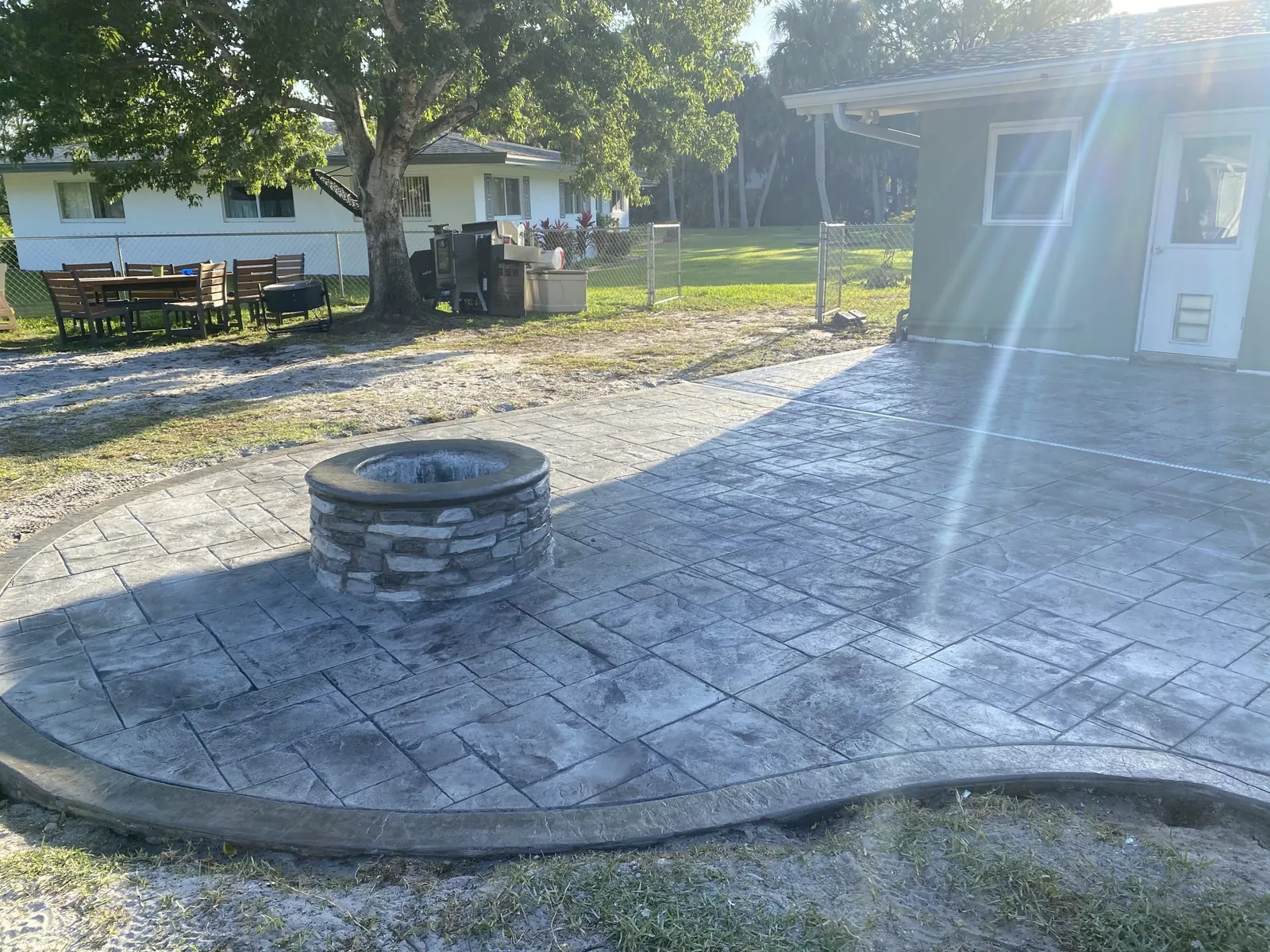 Gray stamped concrete patio around a stone fire pit