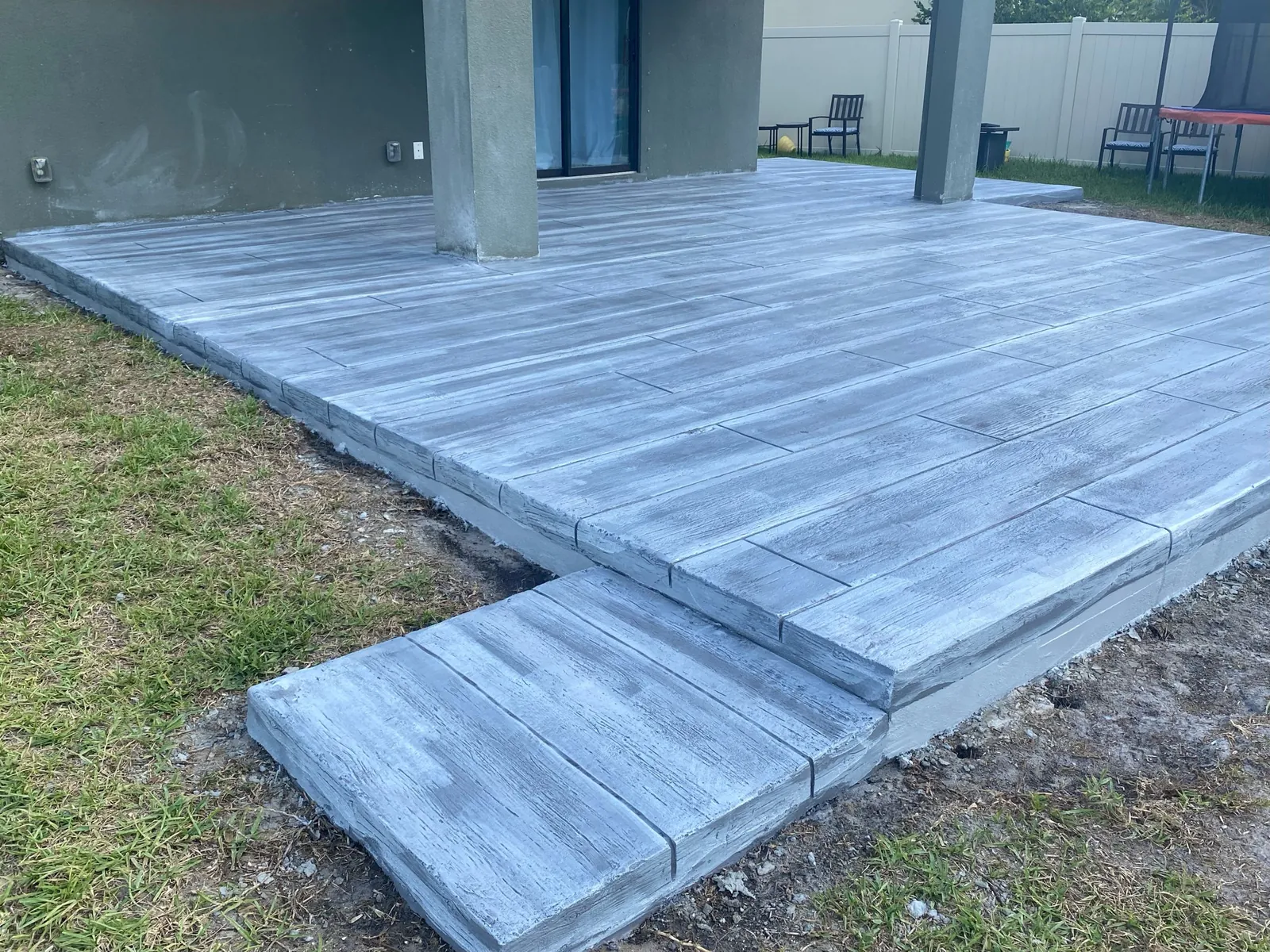 Gray wood plank stamped concrete patio with a step
