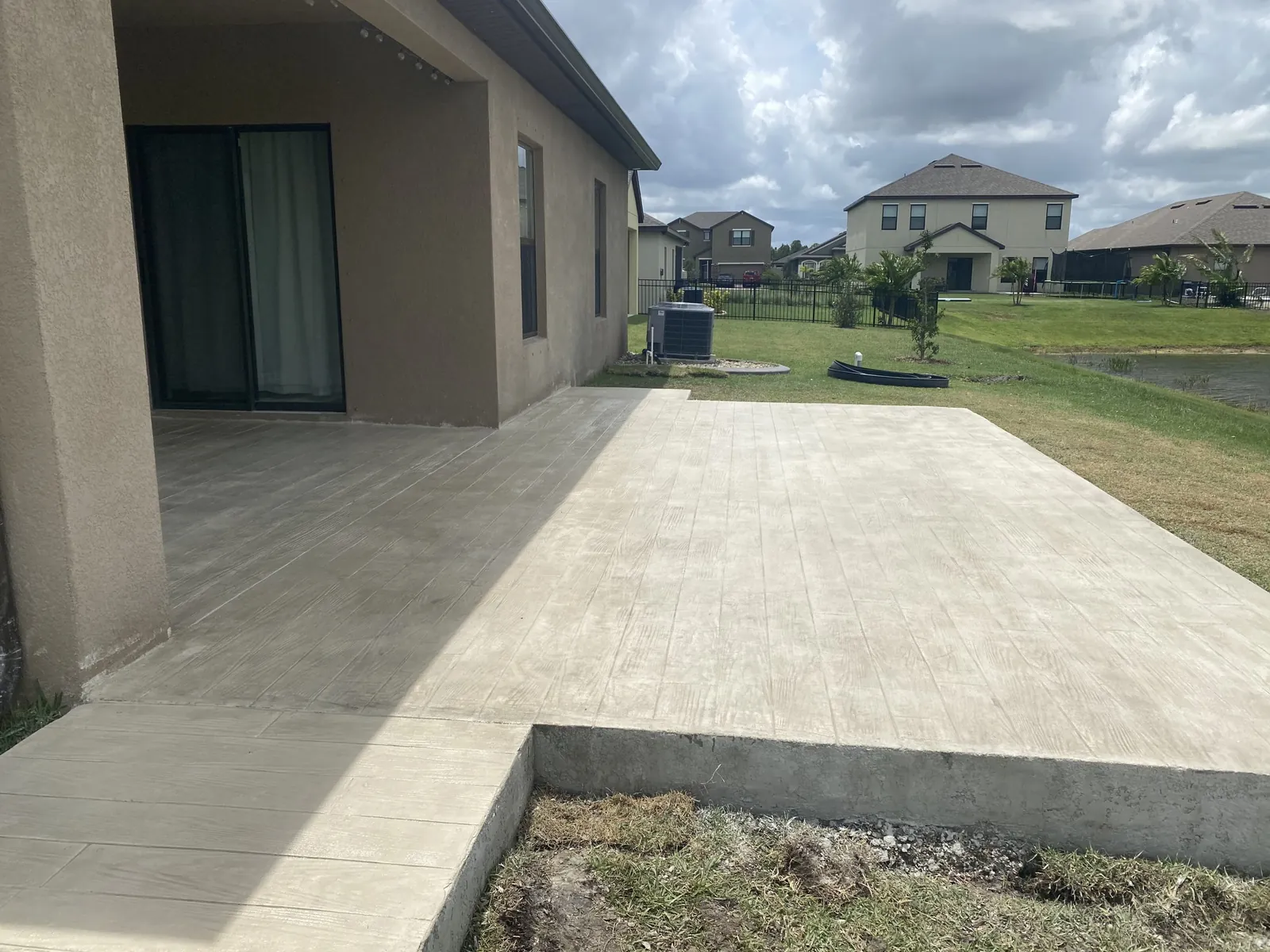 Wood plank stamped concrete patio extension off a covered porch